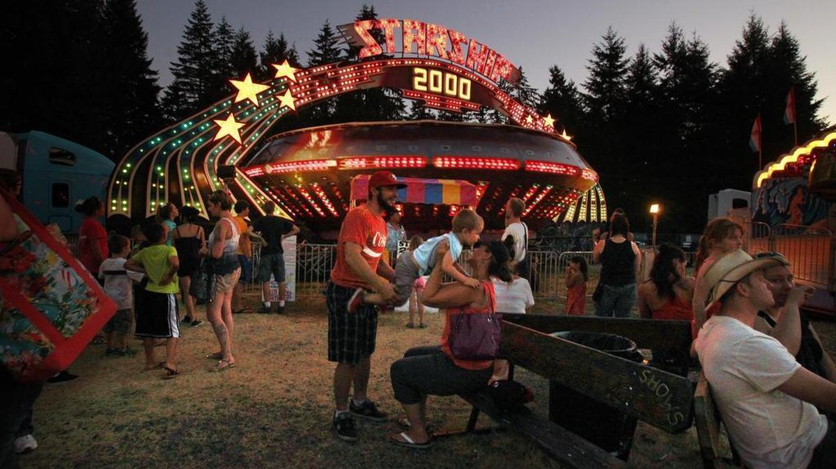 
Fairgoers take in the evening sights at the Davis Shows Northwest carnival during the fair. 
