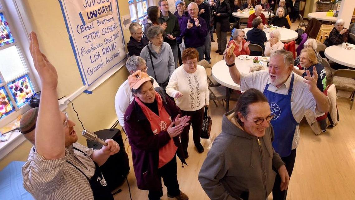 As bagel and blintz lovers line up for tasty treats Sunday, Rabbi Seth Goldstein (left) welcomes them to Temple Beth Hatfiloh's annual Blintzapooza fundraiser with along Oscar Soule, a longtime Blintz event volunteer who raised his bagel in celebration.