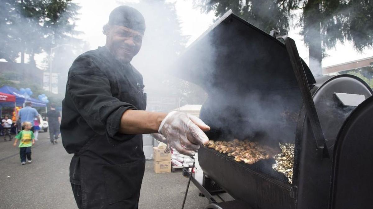 Germaine Harris of Beau Legs Fish & Chips smokes up a rack of chicken drumsticks during the 2016 South Sound BBQ Festival at Hunthamer Park in Lacey.