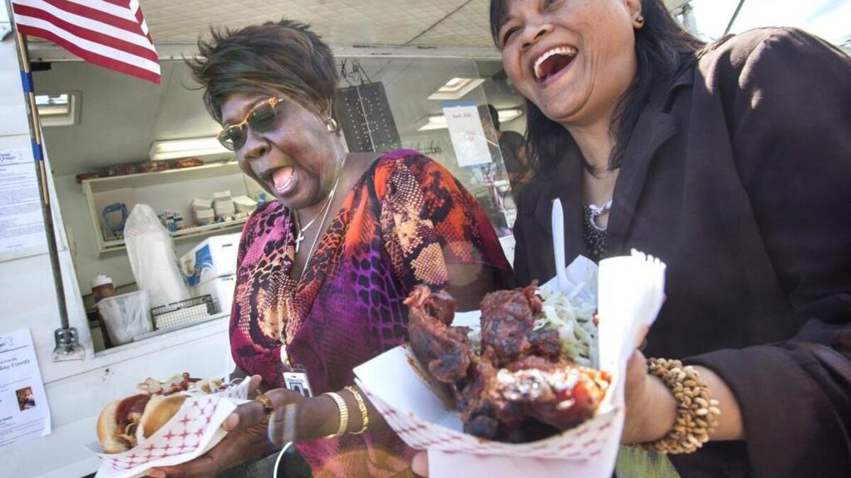 Lillian Dyous (left) of Olympia and Cathy Sablan of Lacey gather up their order from Barb's BBQ booth during lunch at Capital Lakefair in 2016. "We're getting everything: chicken, hot links, ribs," Dyous said. "I'm not here for a salad."