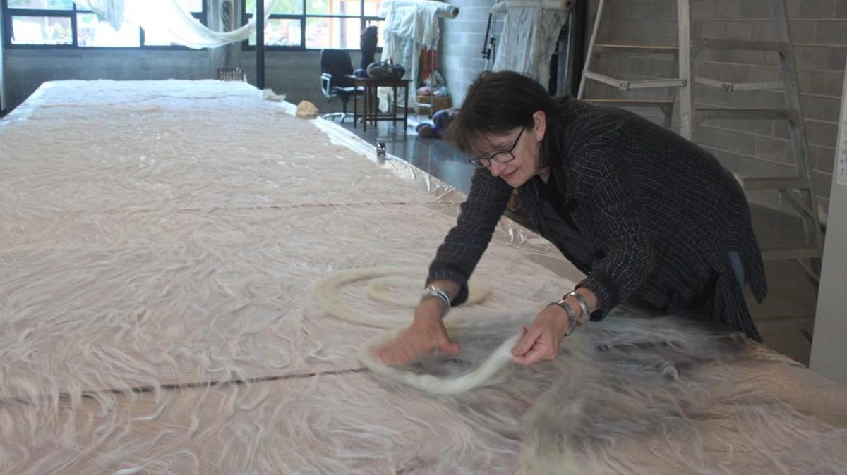 Olympia artist Janice Arnold lays down wool fibers to make a felt hanging at the Steam Plant Building in Olrmpia.