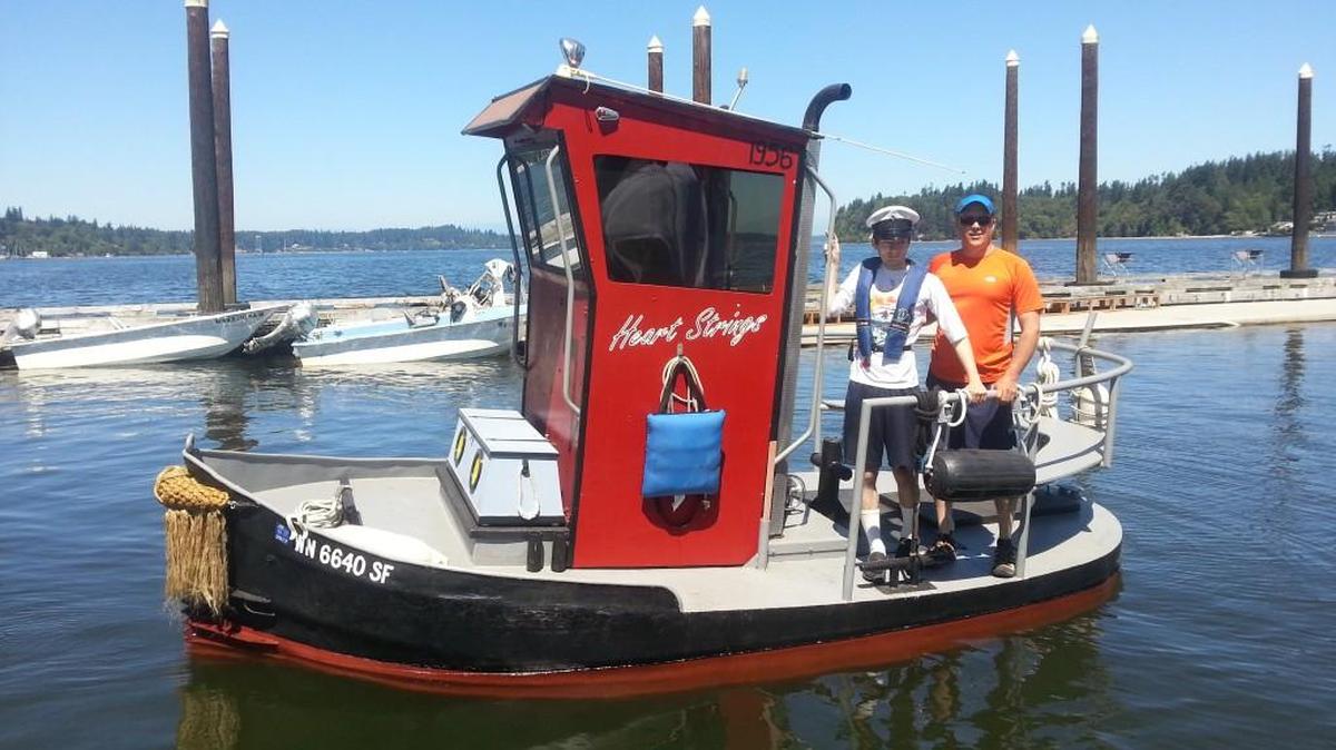 Dillon Graham, left, and his dad, Kevin Graham, on their 16-foot tug, Heart Strings.