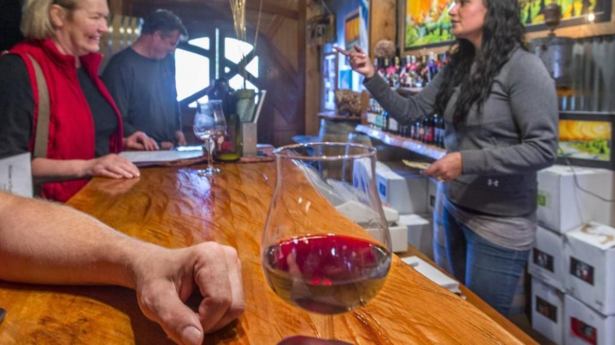 Customer Kerri Wade, left, and employee Kelley Romero chat last month in the tasting room at Harbinger Winery in Port Angeles.
