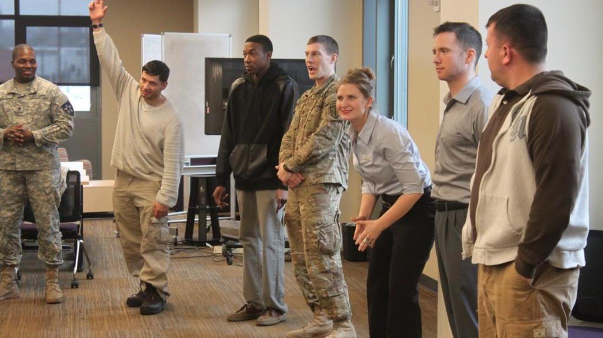 Participants in a Yes Works improv workshop for transitioning military play a circle memory game. Yes Works member Rachel Lionheart (center) helps things along.