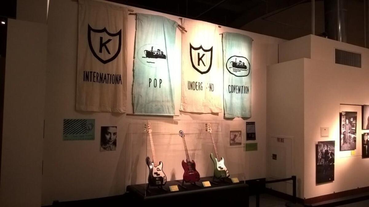 Banners made by Nikki McClure for the International Pop Underground Convention hang behind three guitars on loan from the EMP Museum in Seattle in a display for “A Revolution You Can Dance To” at the Washington State History Museum. The guitars were used by Bikini Kill and Nation of Ulysses, left, Carrie Brownstein of Sleater-Kinney, center, and Donna Dresch, founder of Chainsaw Records.
