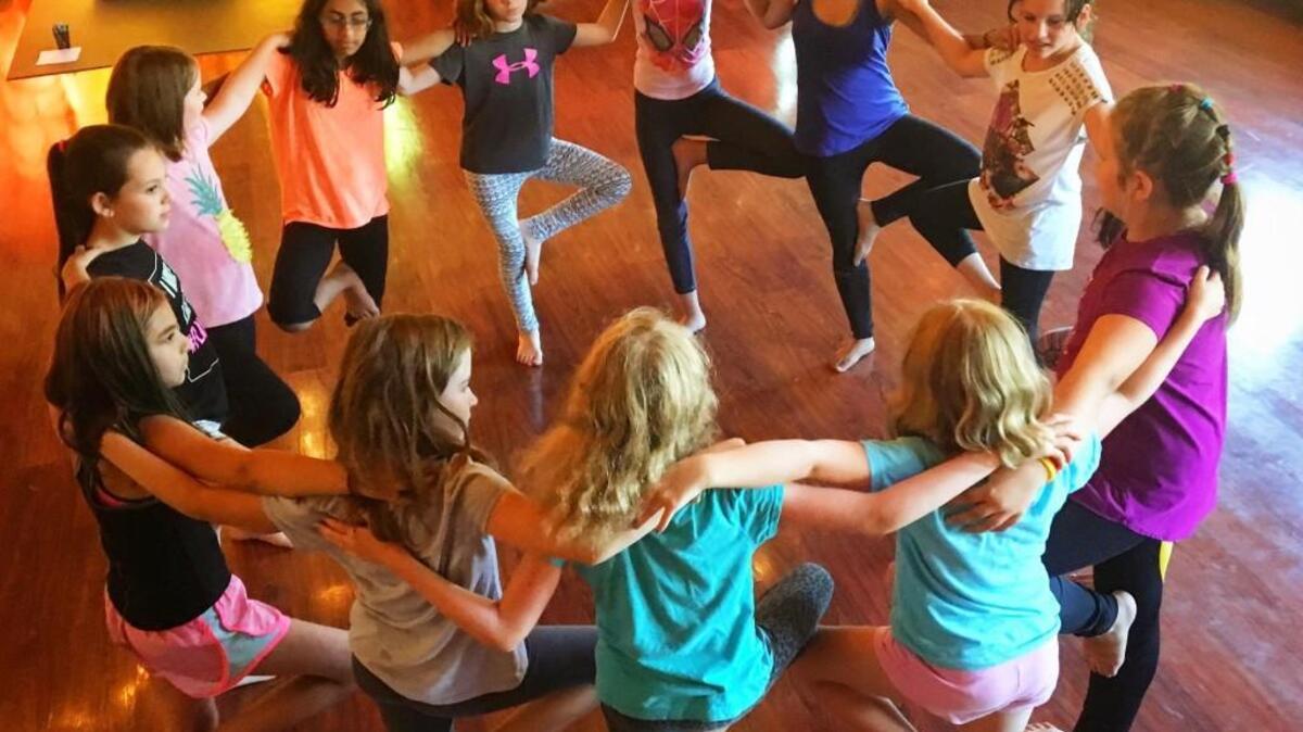 Empowerment 4 Girls campers lean on each other as they learn poses.