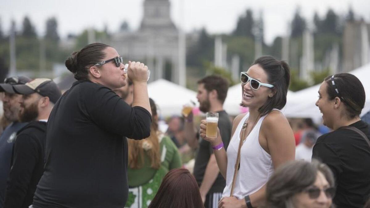 Former Saint Martin’s basketball teammates Krissy Bassett (left) of Rainier and Kelsey Baker of Seattle sample beers along the Olympia waterfront during the Olympia Brew Fest at the Port Plaza on Saturday, Aug. 6, 2016.