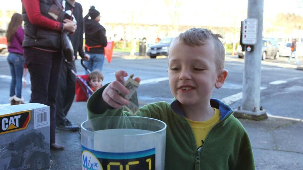 FILE PHOTO: Andy Melvin of Virginia drops a dollar into the donation bucket during the annual MIXX 96.1 Holiday Toy and Fund Drive in downtown Olympia in 2012.