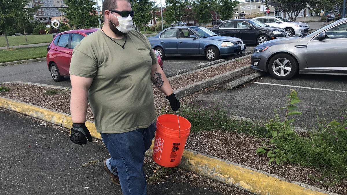 Alex Chambers picks up cigarette butts from a parking lot near Percival Landing in Olympia on Monday afternoon. After spending a few hours picking up trash downtown, Chambers picked up additional litter near his car before heading home.