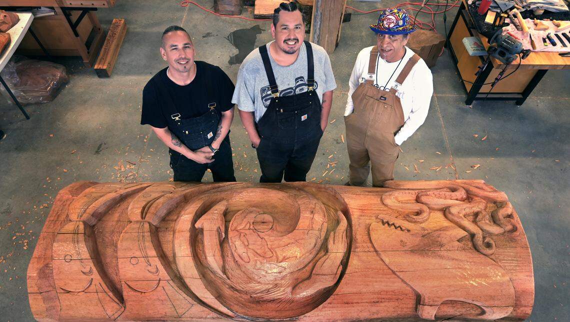 Salish multimedia artist Ed Archie NoiseCat along with apprentices Ablaza Pluff and Earl Pluff continue their carving of the 13-foot story pole honoring Billy Frank Jr. and other Indigenous activists in the Pay3q’ali carving studio during a June 25 work session on the Indigenous Arts Campus at The Evergreen State College in Olympia.The project is part of a six-month residency hosted by the Longhouse Education and Cultural Center.