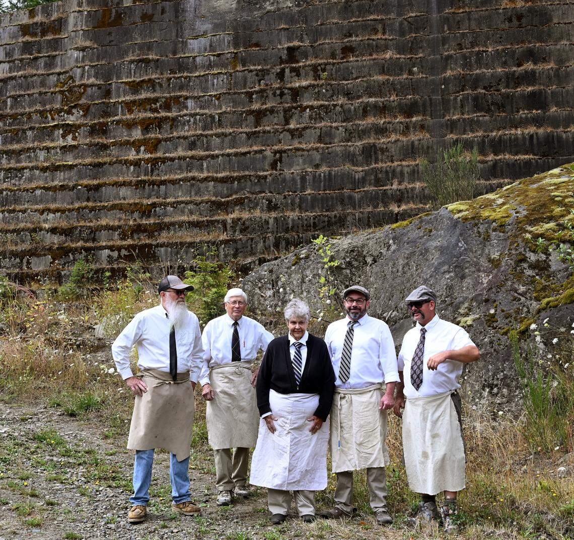 With the massive Hercules #1 Quarry showcased behind them, Tenino Stone Carvers Guild members Tony Cutler, Keith Phillips, Myrna Orsini Bill Lenker and Dan Miller pose for a group photo after an Aug. 16 stone carving class session.