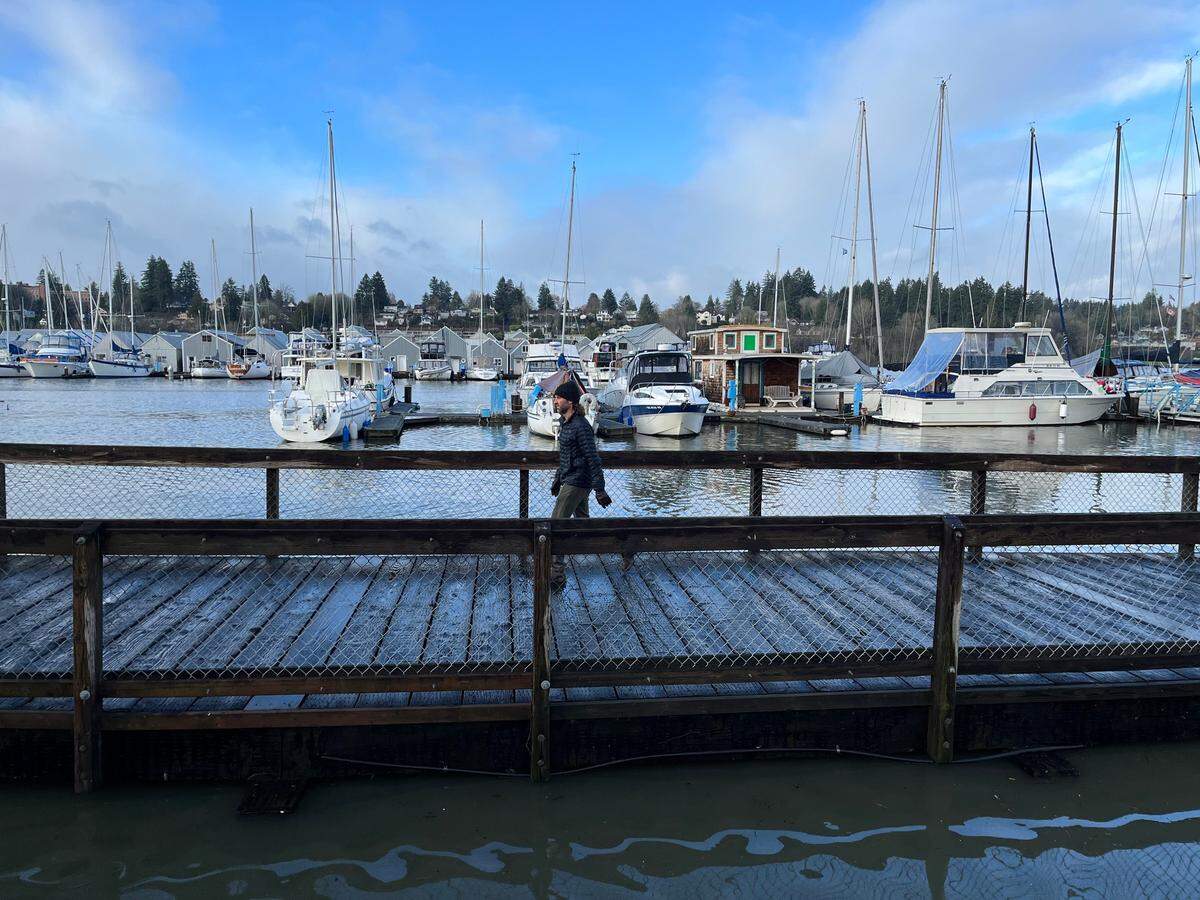 A pedestrian walks along the water at Percival Landing in Olympia during high tide at 10 a.m. on Wednesday, Dec. 28, 2022.