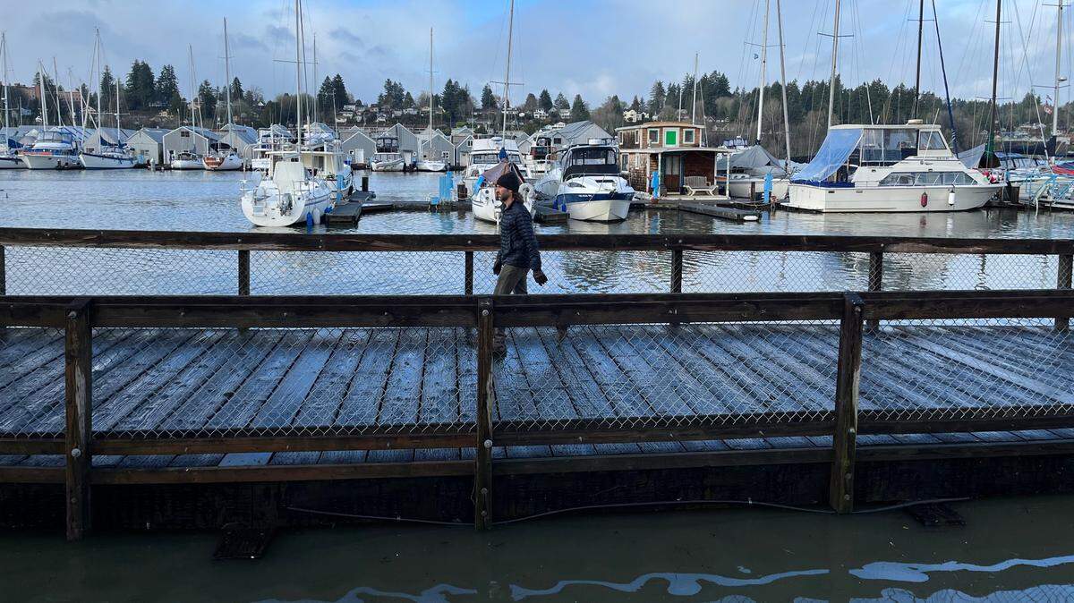 A pedestrian walks along the water at Percival Landing in Olympia during high tide Dec. 28, 2022.
