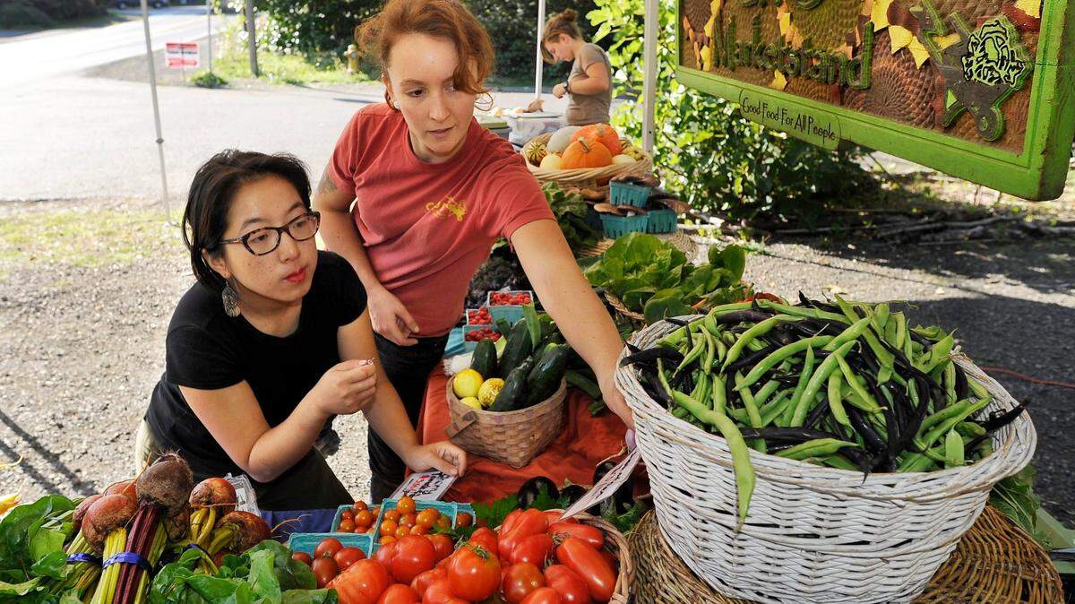 GRuB staff member Quin Baine (right) readies price tags while interns Shinji Moon (left) and Victoria Kantargis set up the produce display before opening GRuB’s produce stand in 2015.