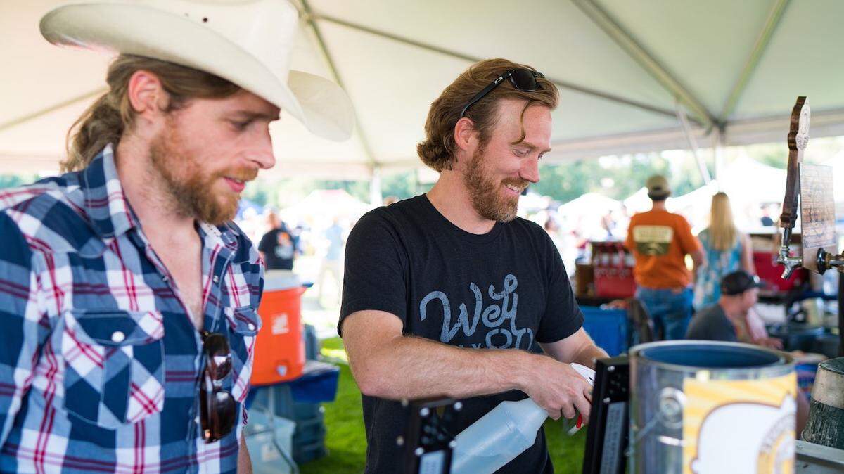 Workers at the Well 80 booth use a spray bottle to wash out tasting cups at the 2019 Tumwater Artesian Brewfest. The Brewfest is back on Aug. 20.