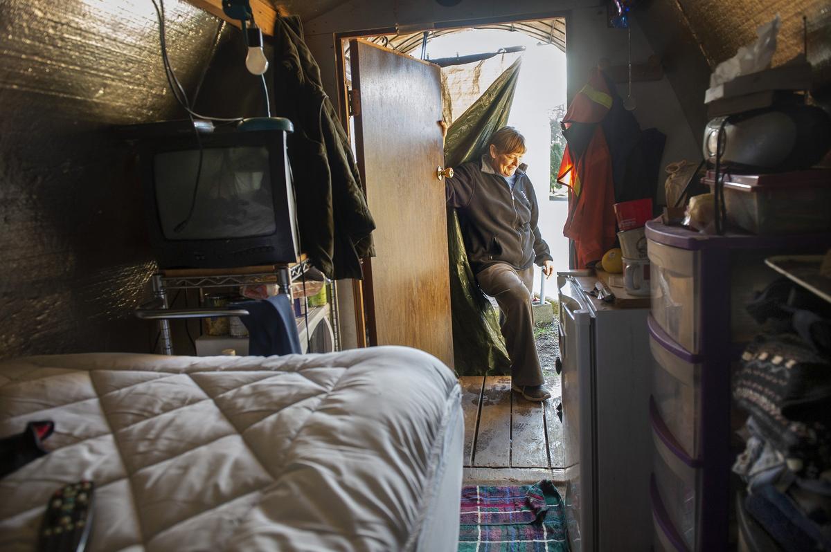 Vickie, a resident at the Unitarian Universalist Church in Eugene, Oregon, stands in the doorway of her Conestoga hut.