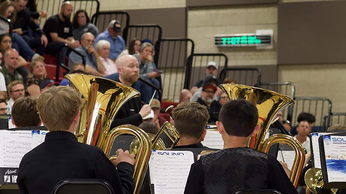 Band director conducts a piece as three students play the baritone.