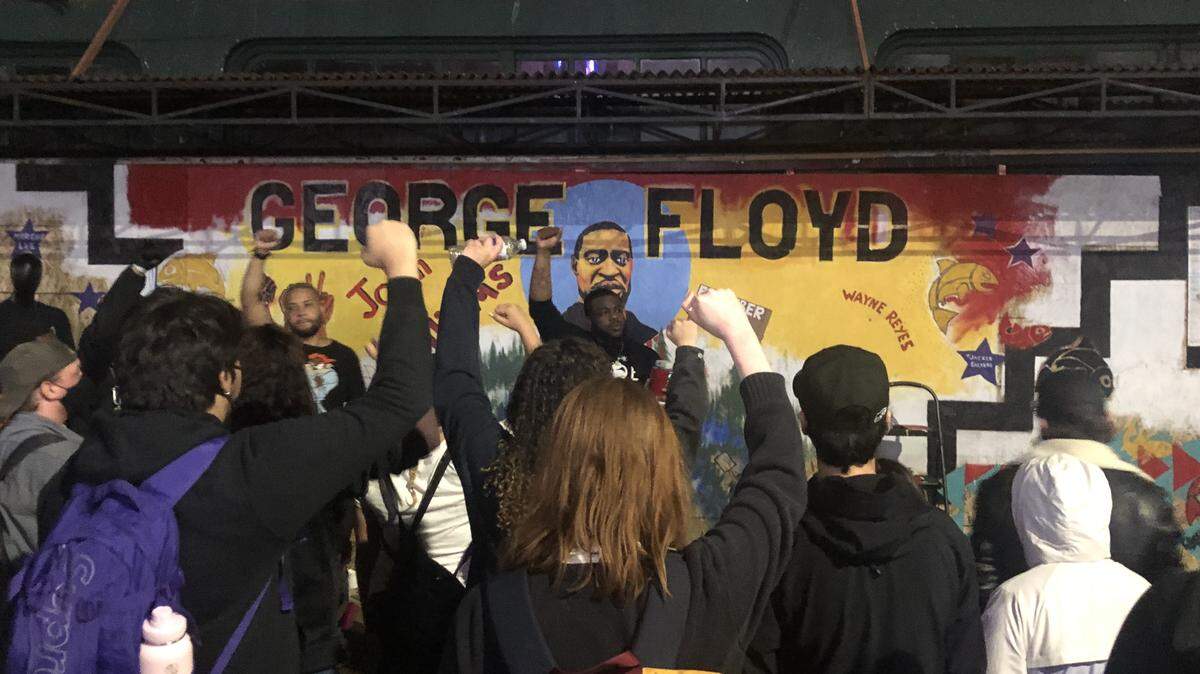 Demonstrators rally in front of a George Floyd mural painted on plywood boarding up the Buck’s Fifth Avenue building on Fifth Avenue in downtown Olympia. Demonstrators told personal stories of their encounters with racism during the seventh day of protests prompted by the death of Floyd, a black man who died in police custody in Minneapolis May 25.