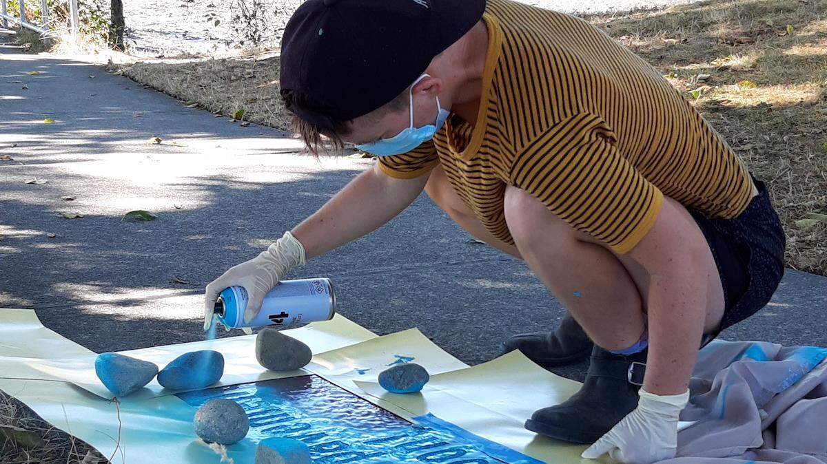 Sady Sparks, Olympia’s poet laureate, paints one of the poems in “Here We Are Magic,” an exhibit of sidewalk poetry written by Sparks and Seattle poet Zyna Bakari, who Sparks has know since attending high school in Yellow Springs, Ohio. The poets used spray paint to share their work on the sidewalks along East Bay and West Bay drives and rain-activated paint — visible only when it’s wet — at Percival Landing, the Olympia Farmers’ Market and Priest Point Park.