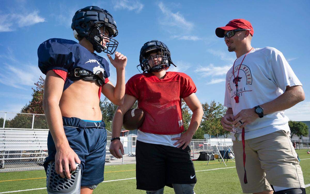 Black Hills senior wide receiver Xander Shepler and sophomore quarterback Jaxsen Beck talk with head coach Garrett Baldwin during football practice at Black Hills High School in Tumwater, Washington, on Wednesday, Sept. 21, 2022.