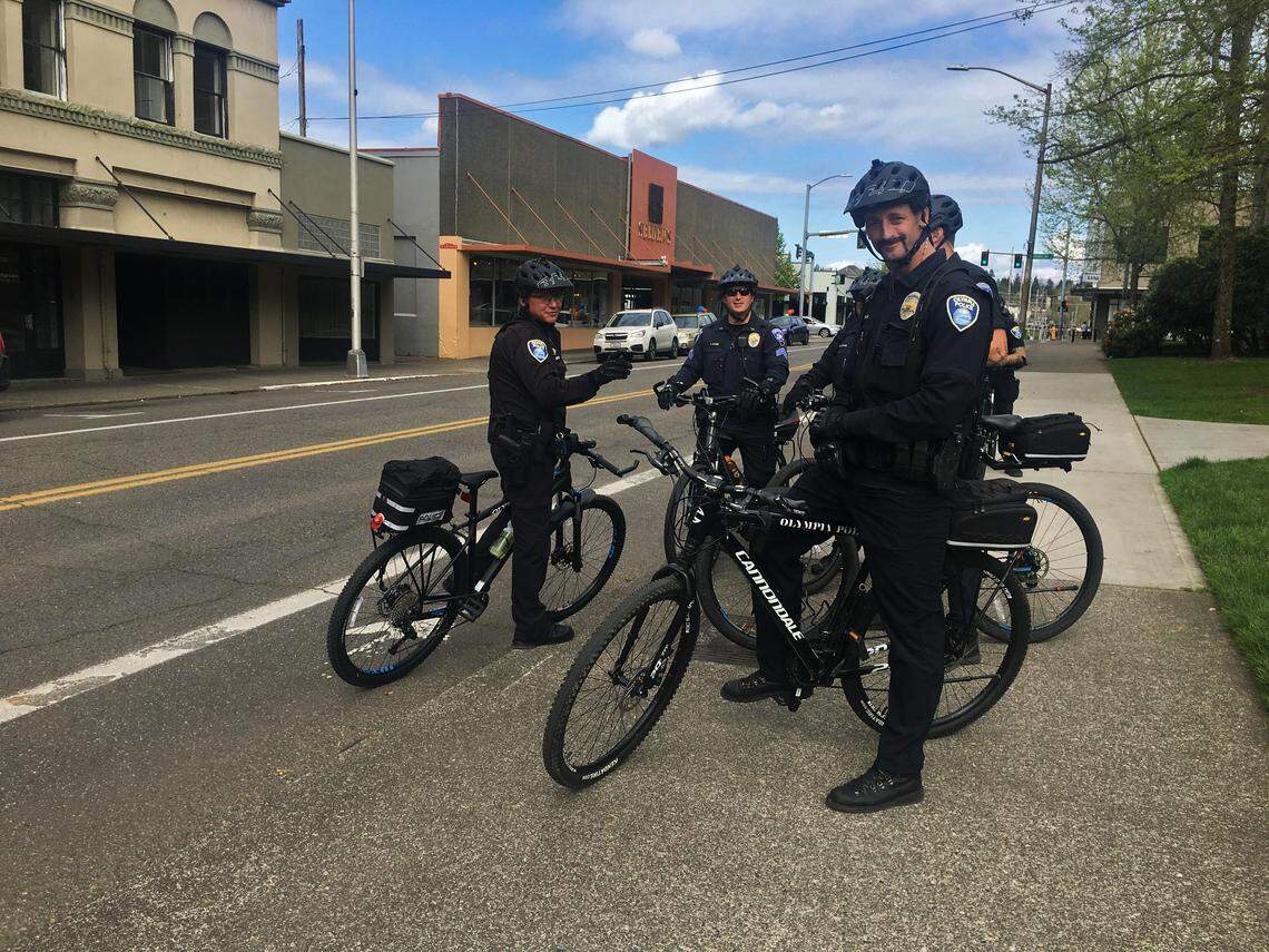 Olympia Police Department officers watch a gathering at Sylvester Park from a neighboring street on Tuesday, May 1, 2018. Officers on bikes were stationed in several locations around downtown Tuesday afternoon.