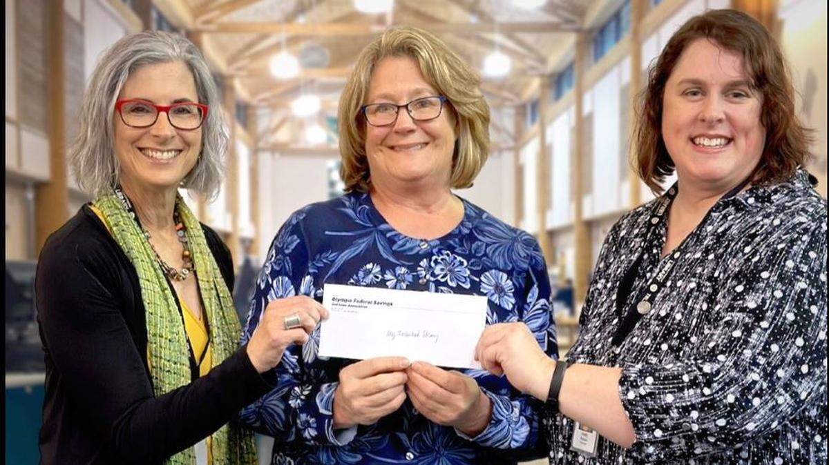 Timberland Regional Library Executive Director Cheryl Heywood (left), executor Debra Johnson and Lacey branch manager Holly Paxson hold the $920,000 check the branch received from the estate of Rodney Maupin.