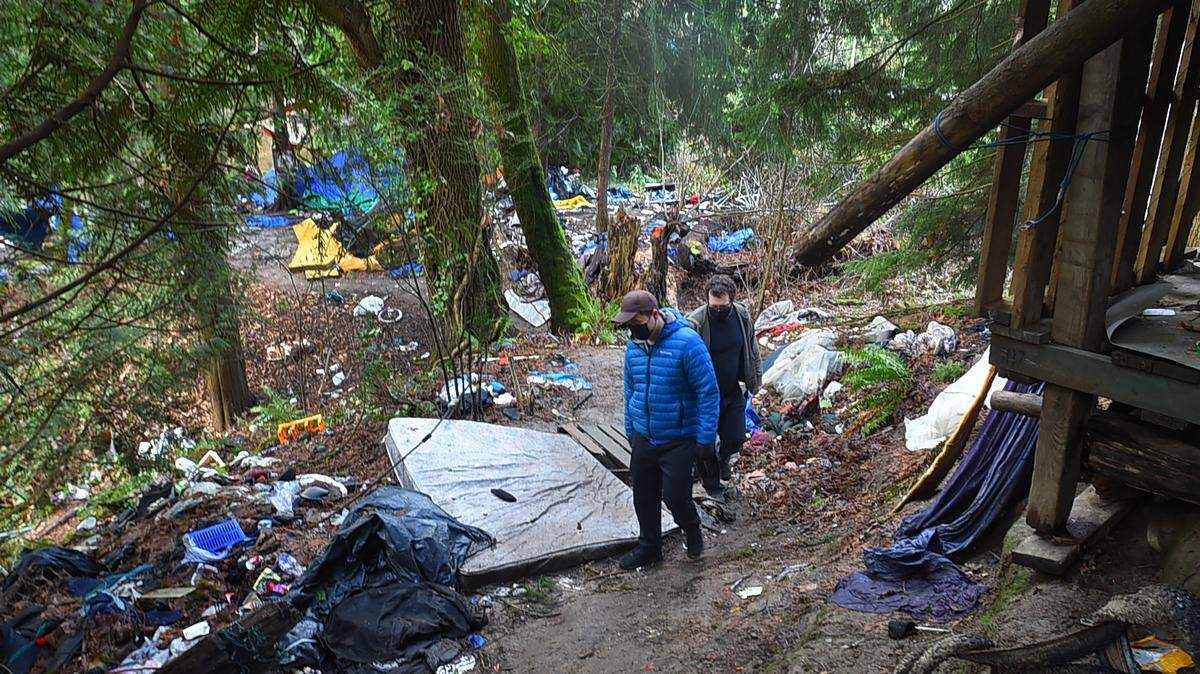 John Lee (left) and Griff Masters walk through the homeless camp on Wheeler Avenue in Olympia in January announcing the arrival of free meals as part of an outreach program by Lee’s family and the Kurios Church.