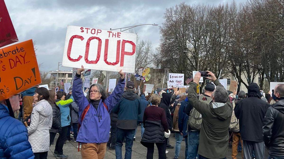 A protester holds a sign stating, “STOP THE COUP” during the 50501 Movement’s protest in Olympia on Monday, Feb. 17, 2025.