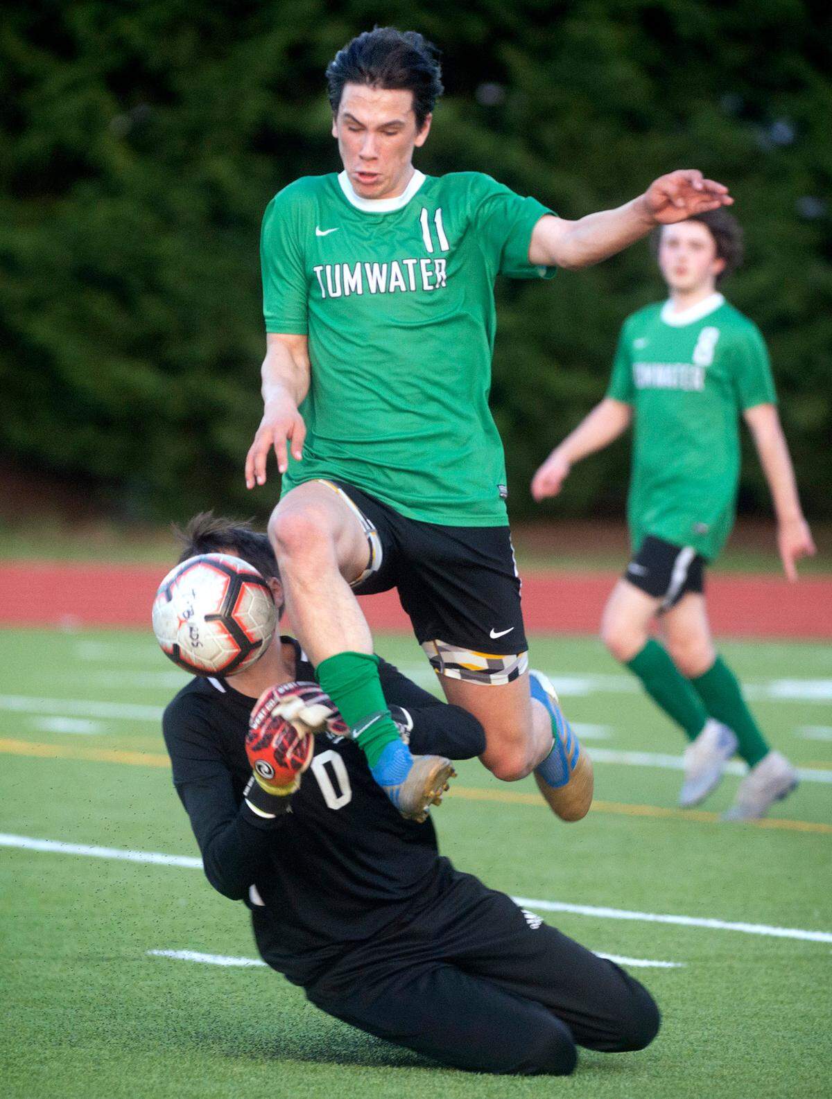 Tumwater junior forward Zach Schmidt flies past Rochester goalkeeper Brady Moen during a soccer match at Tumwater District Stadium in Tumwater, Washington, on Friday, April 16, 2021.