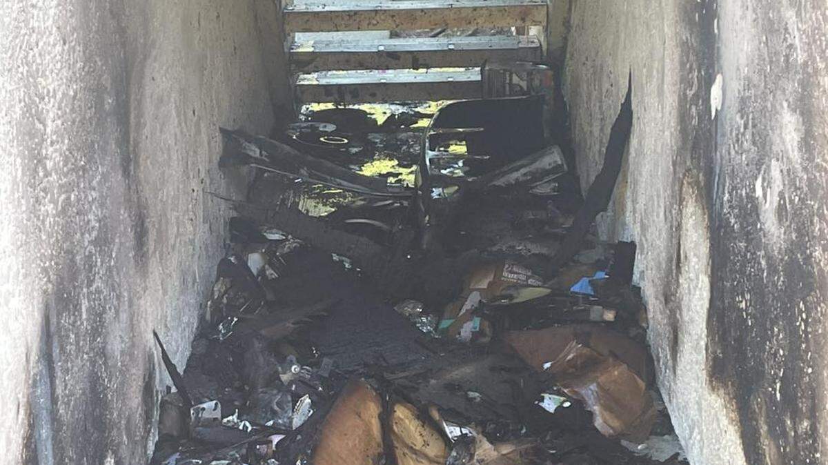 Rubble sits beneath a set of stairs surrounded by white walls scorched by fire. 