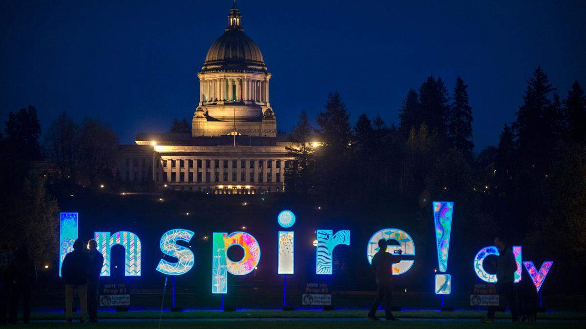 With the state Capitol in looming in the background the Inspire! Oly art installation shines under black lights at Heritage Park in downtown Olympia, Washington, on Saturday, March 26, 2022. The project promotes Proposition 1 - aka the Cultural Awareness Initiative - allocating 1/10th of 1% of a statewide sales tax to support and provide access to the arts.