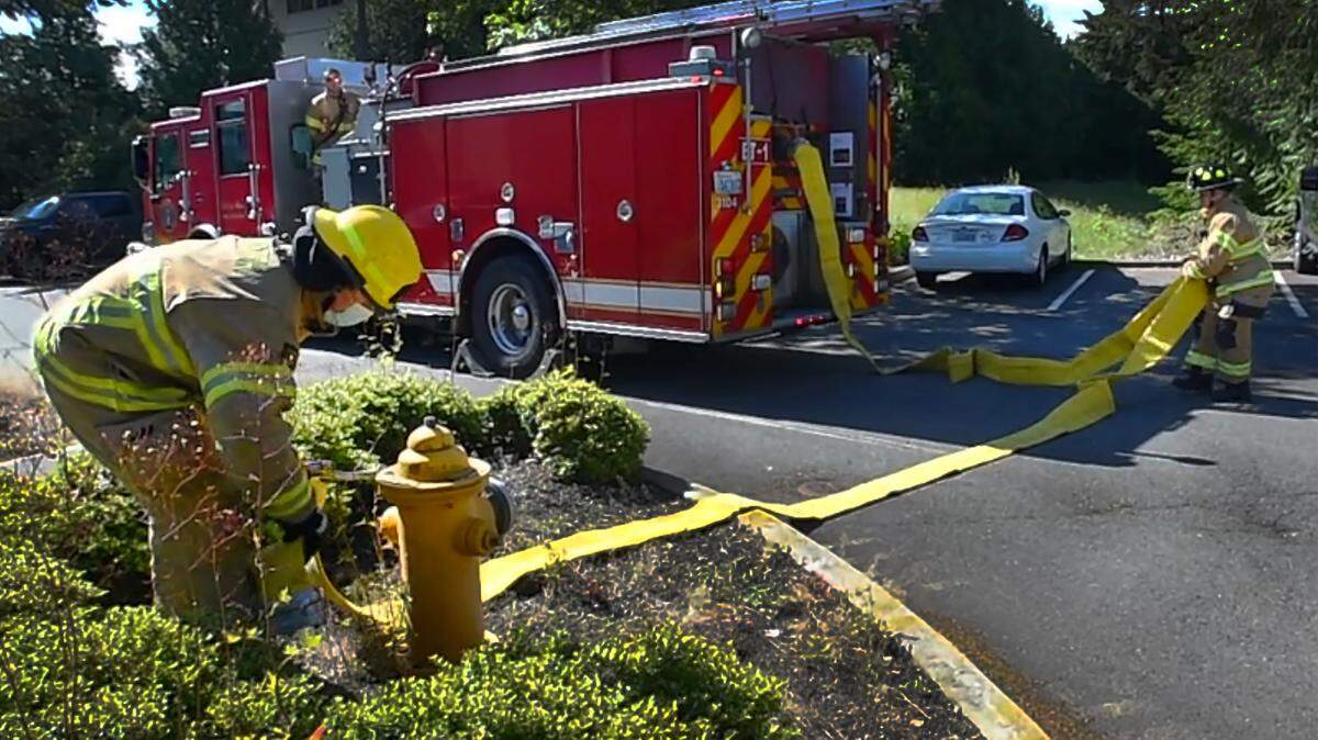 Outside of the Tumwater Fire Department Headquarters Station, a volunteer firefighter couples a hose with station firefighters during a training drill. The cities of Olympia and Tumwater have laid out a timeline to hopefully combine the cities’ fire departments under one Regional Fire Authority. 