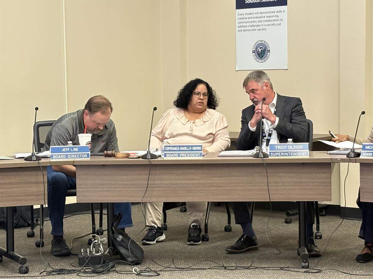 North Thurston Public Schools board President Esperanza Badillo-Diiorio (center) huddles with board member Jeff Line (left) and Superintendent Troy Oliver during a break in the school board meeting on Thursday, May 7.