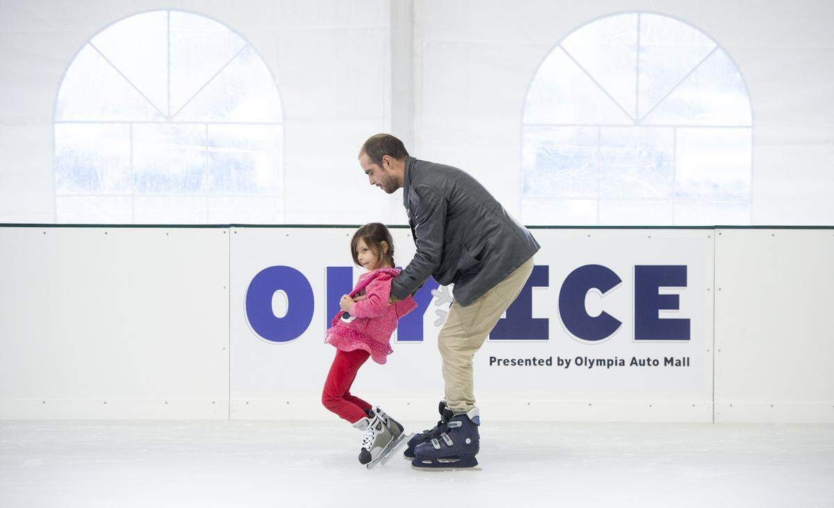 Michael Looney of west Olympia helps his daughter, Cara Looney, 5, as they hit the ice for the opening day at Oly on Ice temporary skating rink at Isthmus Park in downtown Olympia in 2018. The rink opens for the holiday season and beyond on Friday afternoon.