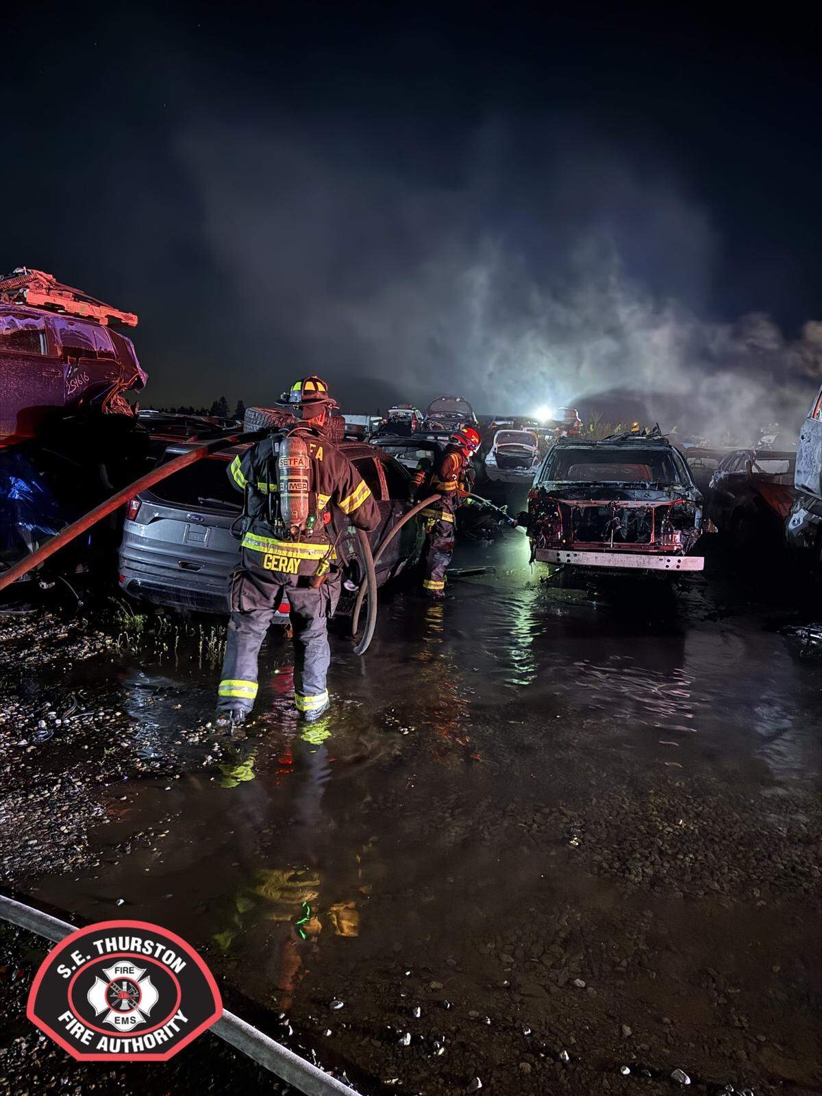 Firefighters extinguish a blaze that burned many cars at a vehicle wrecking yard on Northern Pacific Road Southeast in Yelm in the early hours of Thursday, April 30.