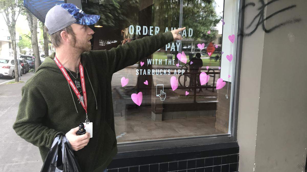 Olympia resident Jeff Jones points out graffiti that still remains on the Starbucks at Legion Way and Capitol Way Tuesday morning in Olympia. Jones, along with others, kept protesters from breaking the windows on Monday evening.