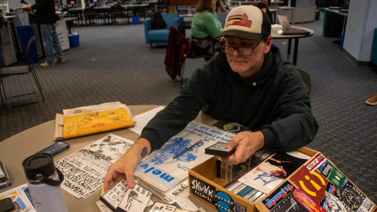 Olympia resident and musician Sean McCoy flips through cassette tapes he has been collecting since high school at Olympia Timberland Library. McCoy grew up surrounded by the music scene in Olympia, which inspired him to start playing the bass guitar. He brought the items to the library Tuesday, Jan. 31, 2023, for an event aimed at documenting the city’s place in the history of independent music.