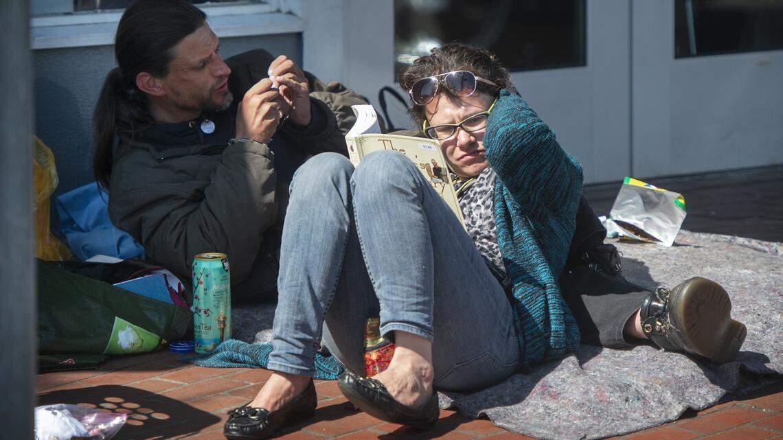 A couple sits outside the Providence Community Care Center in downtown Olympia last week. The City Council says it wants to support the center while mitigating impacts on nearby businesses.