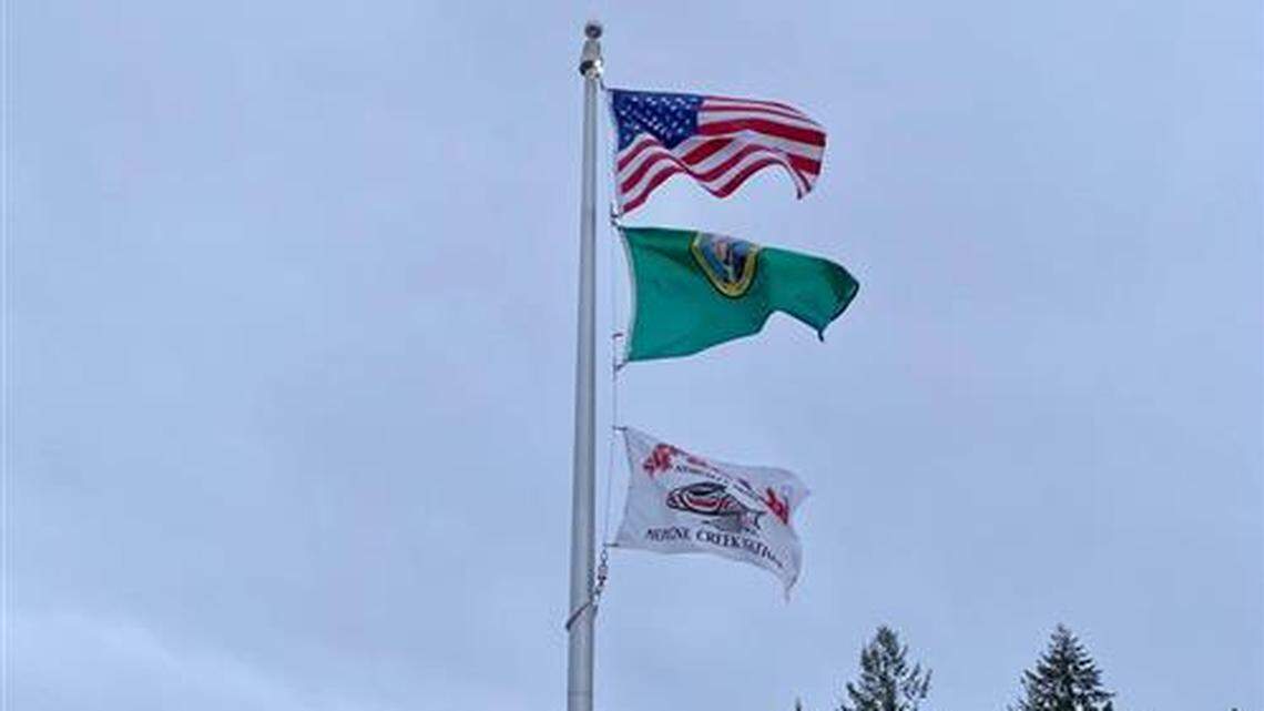 The Nisqually flag flies alongside the United States and Washington state flags outside a North Thurston Public Schools building.