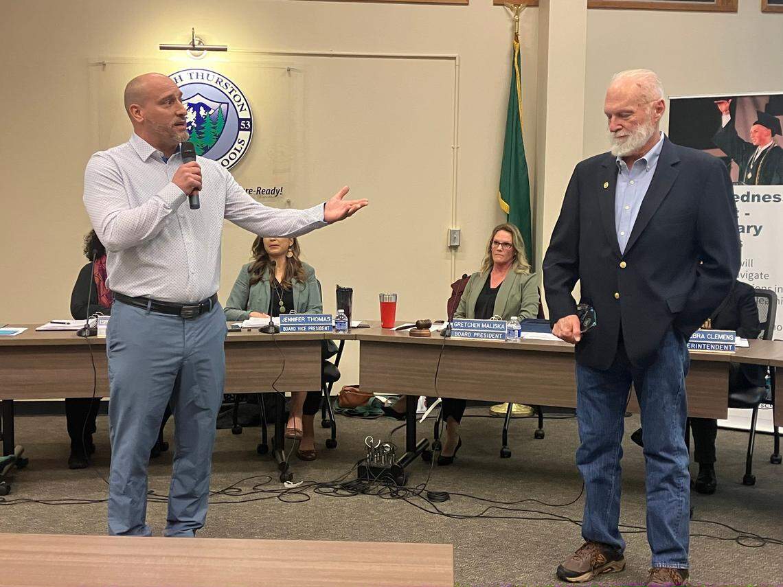 Departing North Thurston Public Schools board members Dave Newkirk (left) and Graeme Sackrison address the school board and audience during Tuesday’s school board meeting.