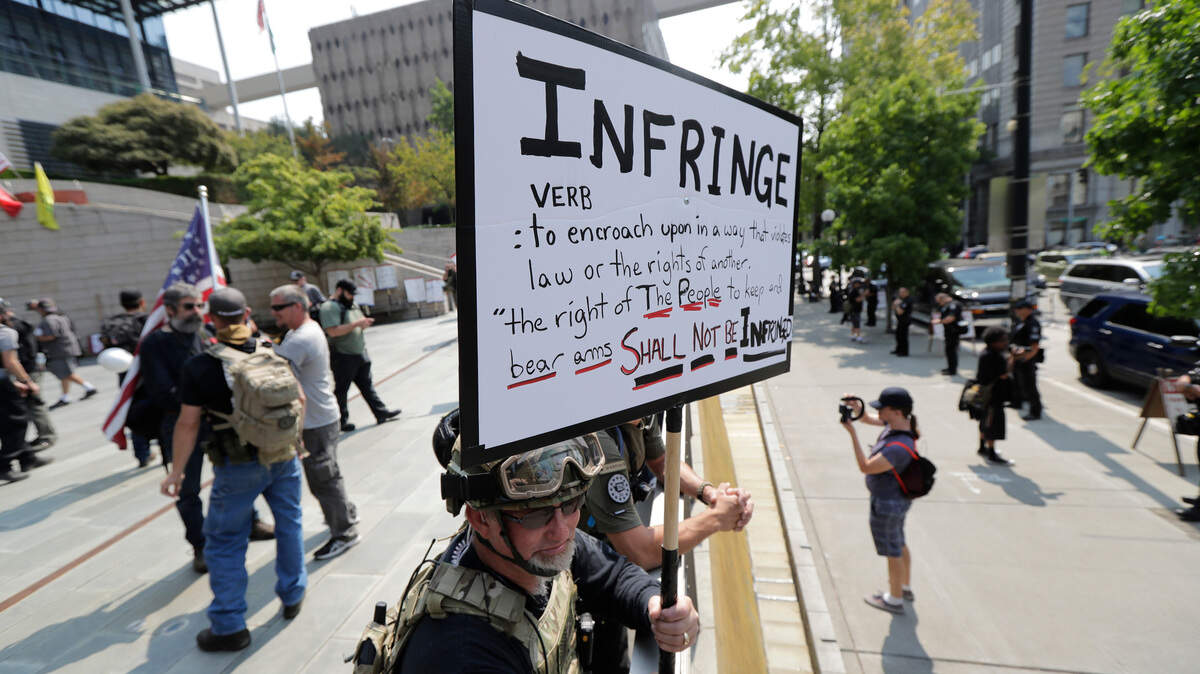 A protester stands on the side of the street with members of Patriot Prayer and other groups advocating for gun rights at a rally, Saturday, Aug. 18, 2018, at City Hall in Seattle.