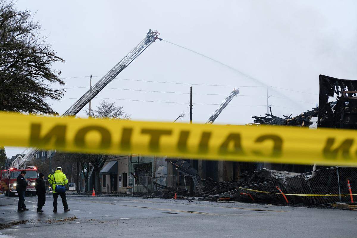 A firefighter shoots water onto the remains of an apartment building at 310 Capitol Way North, Olympia on Wednesday, Dec. 15, 2021. The building was under construction when it was destroyed.