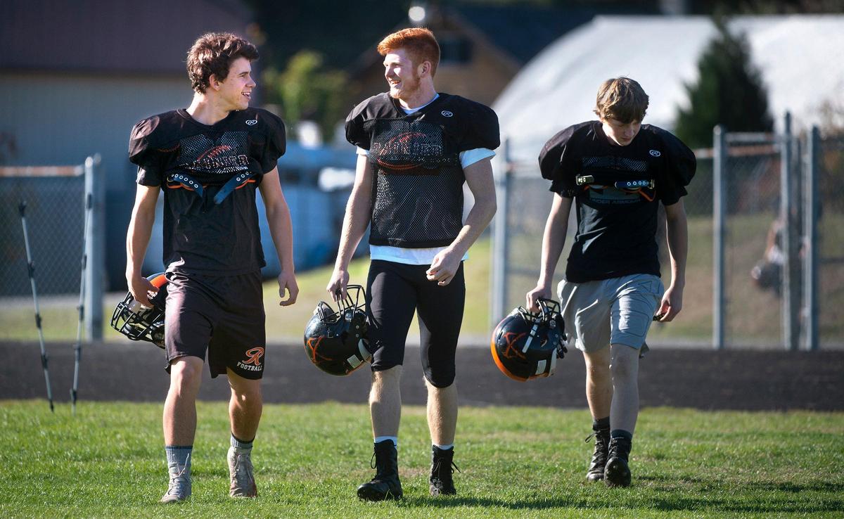 Rainier running back Brody Klein (center) arrives for football practice alongside teammates Sean Mahaffey (left) and Kyle Peterson at Rainier High School on Thursday, Oct. 10, 2019.