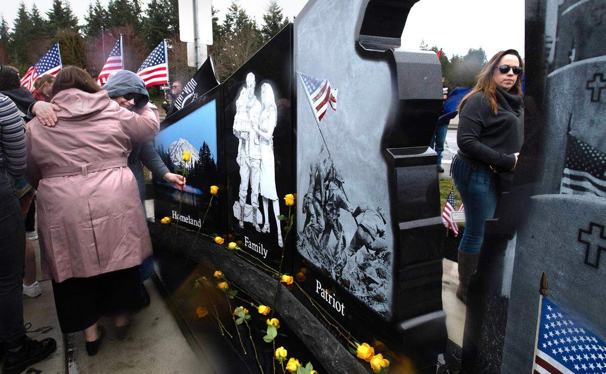 Jennifer Parmar of Rainier receives a hug as she places a yellow rose to honor her late husband, Iraq War Army veteran Sfc. Abraham Parmer, during the dedication and unveiling of the new Gold Star Families Memorial Monument at the Lacey Civic Plaza on Friday, March 31.