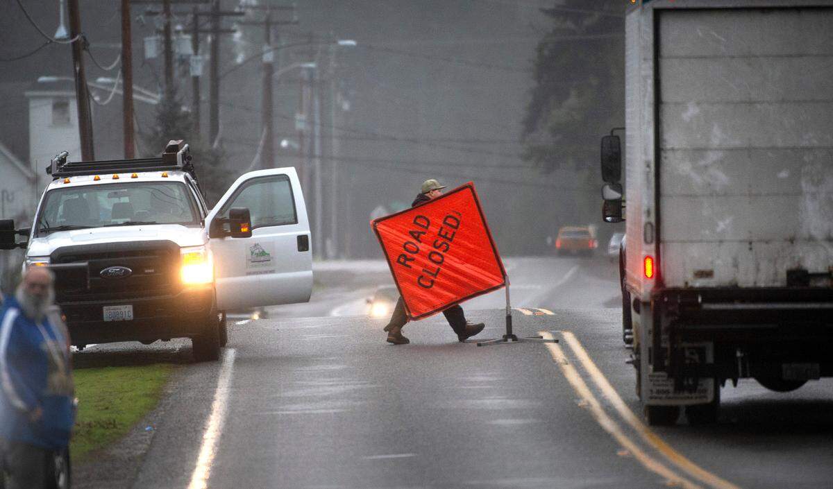 A Thurston County road crew worker closes 128th Avenue in Littlerock, Washington, because of floodwaters from the Black River over the roadway on Friday, Jan. 7, 2022.
