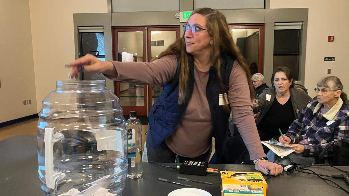 Aldea Glen homeowners’ association resident Amy Gardner drops a slip of paper into a plastic jug during a special meeting Tuesday to elect new board members. The meeting was held at the Lacey Community Center.