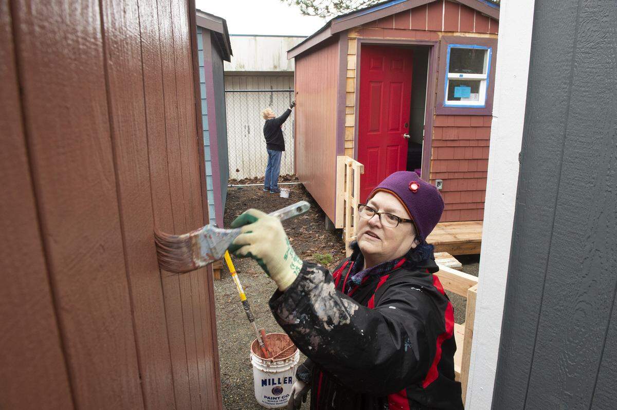 Ann Livermore of Olympia and Inez West of Lakewood paint tiny houses Jan. 26 ahead of the opening of Plum Street Village.