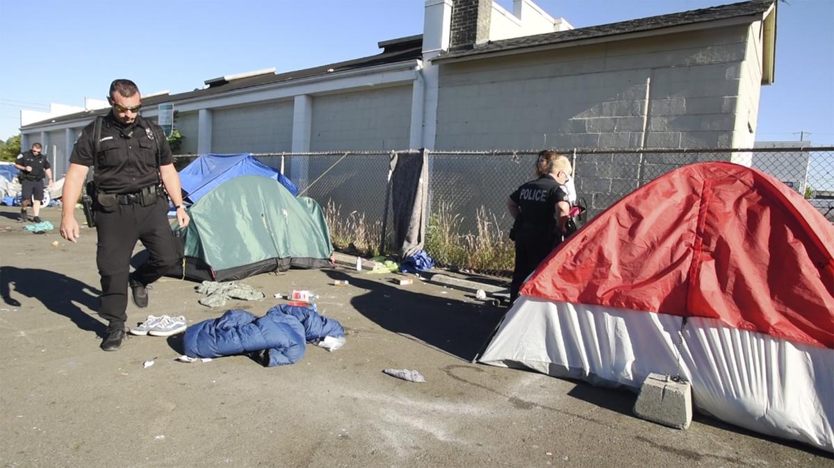 Olympia police Sgt. Amy King along with Walking Patrol Officers Sean O’Brien (center) and Josh Marcuson check on homeless people who’ve camped out in varies sport in the downtown area during their early morning rounds July 12th.