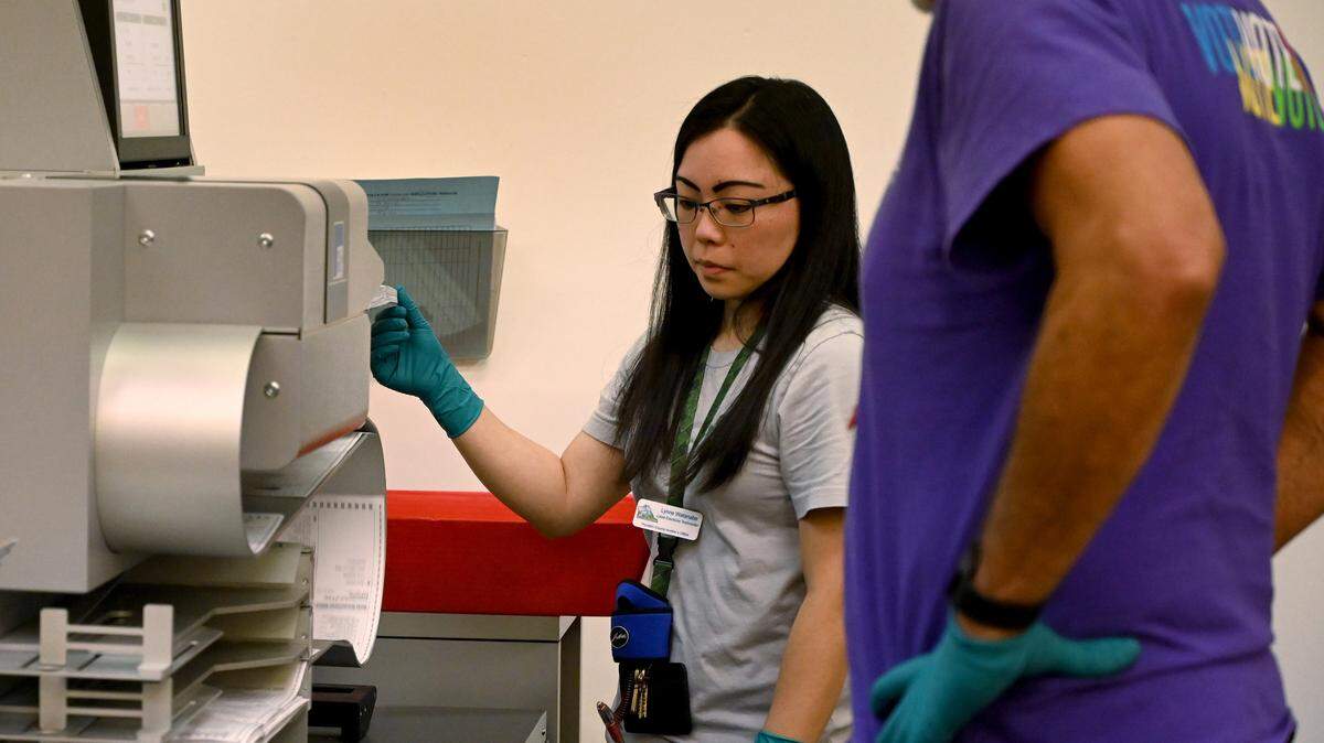 Lynne Watanabe runs a ballot scanner at the Thurston County Ballot Processing Center.