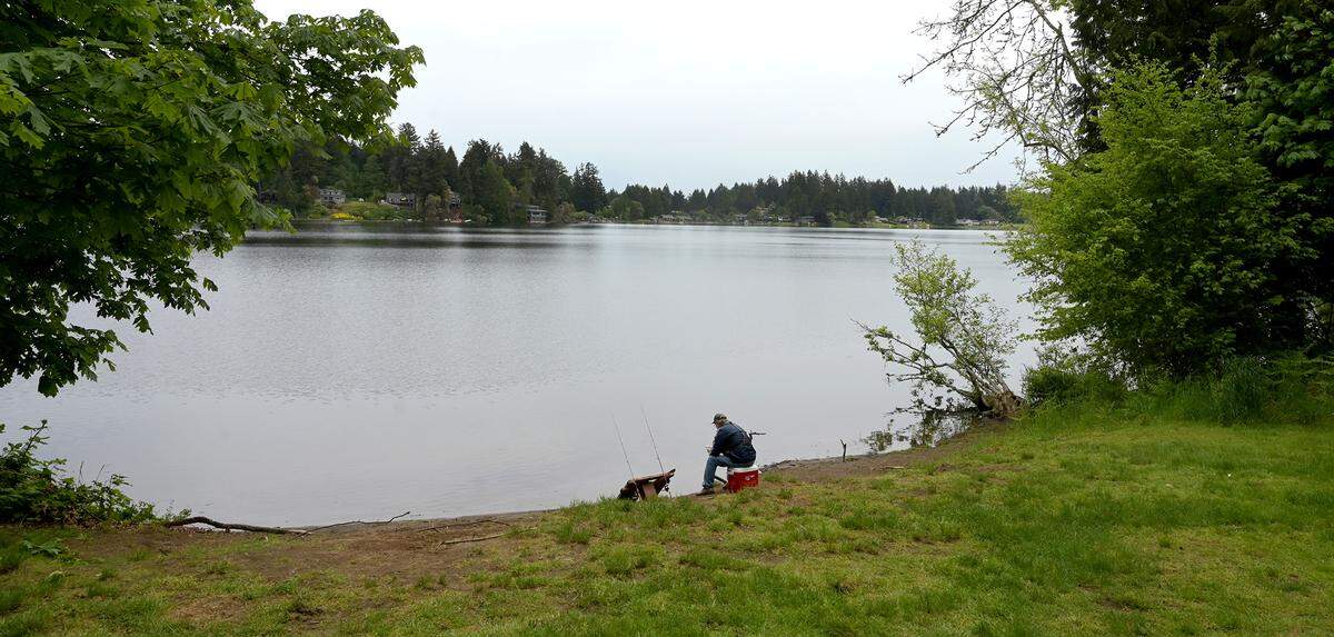 A fisherman enjoys a pleasant Thursday afternoon along the shoreline at Wanschers Park in Lacey, WA. on May 26, 2022. The park is close to a controversial housing project that many nearby residents are opposing